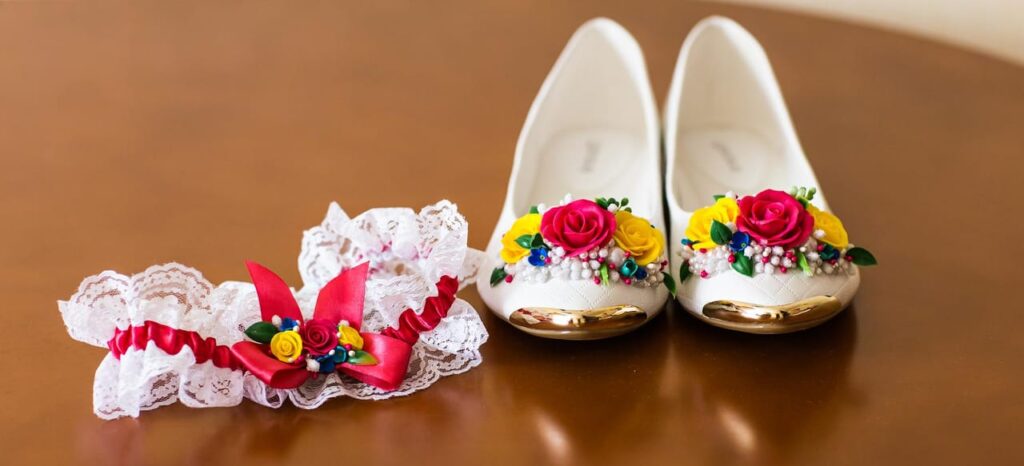 Zapatos y liga de boda con flores coloridas.