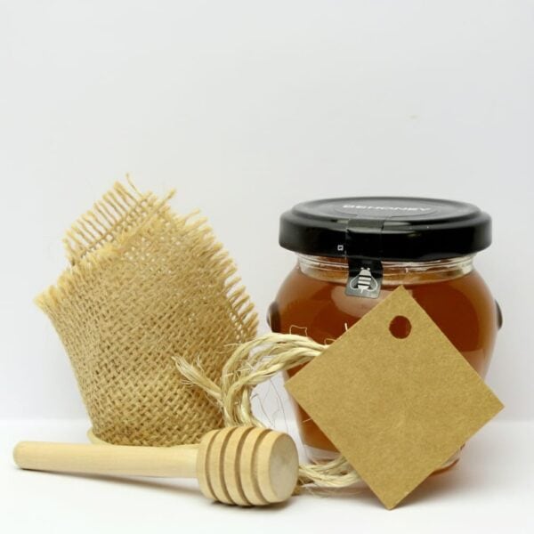 Tarro de miel con cuchara de madera y etiqueta