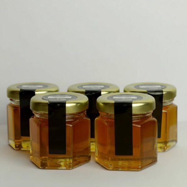 Cinco tarros de miel con tapa dorada