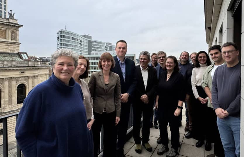 1. Gruppe von Menschen auf Dachterrasse mit Blick auf Berliner Stadtbild, Business Kleidung.