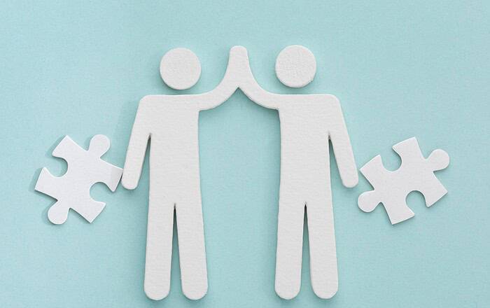 Zwei Figuren mit Puzzlestücken, symbolisieren Zusammenarbeit im Bereich frühkindliche Bildung.