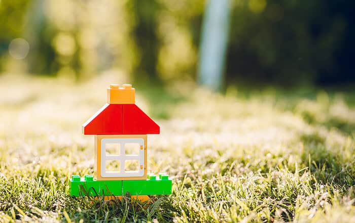 LEGO-Spielzeughaus auf Wiese im Sonnenschein, kindgerecht gestaltet.