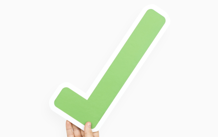Hand hält grünen Haken, symbolisiert Unterstützung für verpflichtendes Kita-Jahr.
