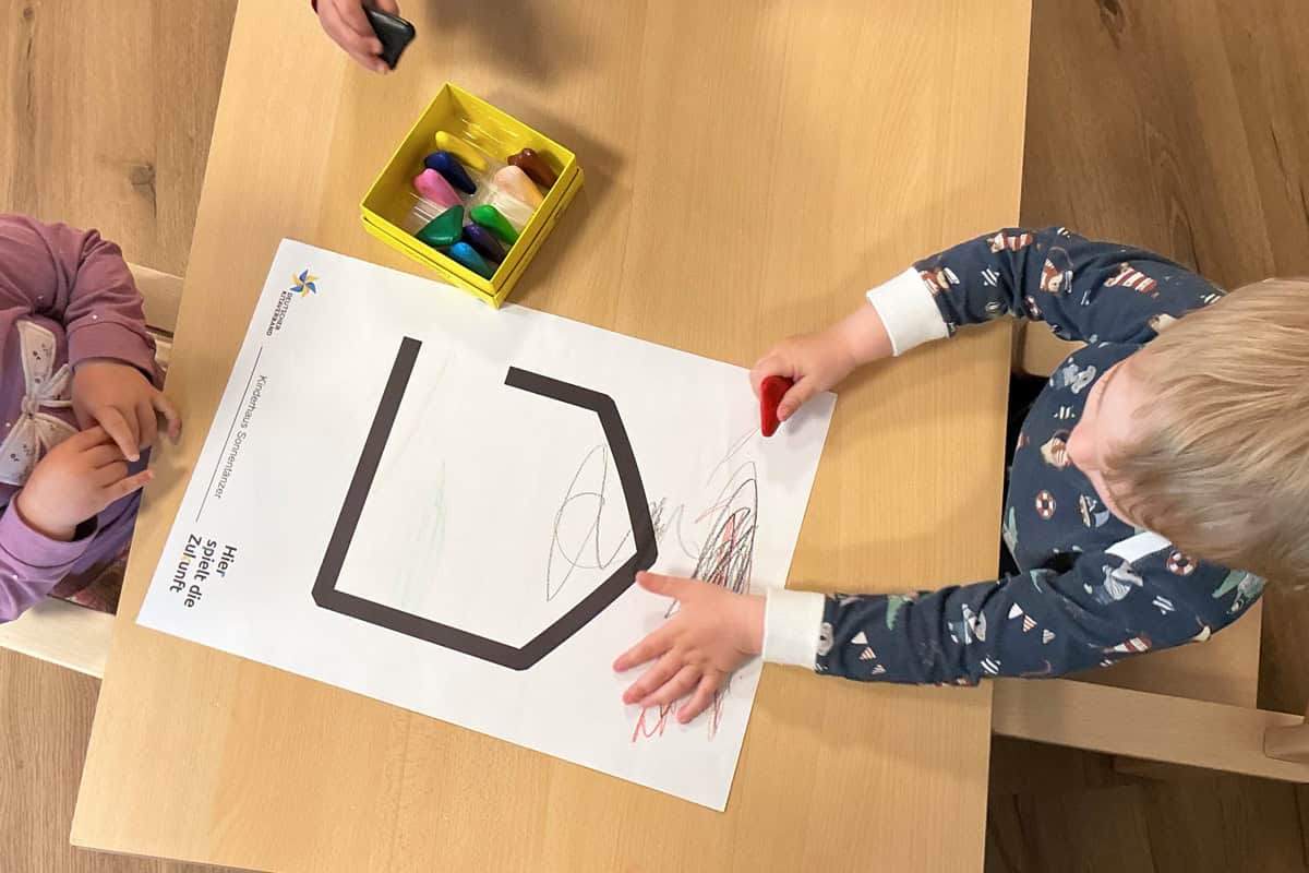 Kinder malen auf einer Schablone mit bunten Kreiden, kreative Aktivität im Kindergarten.