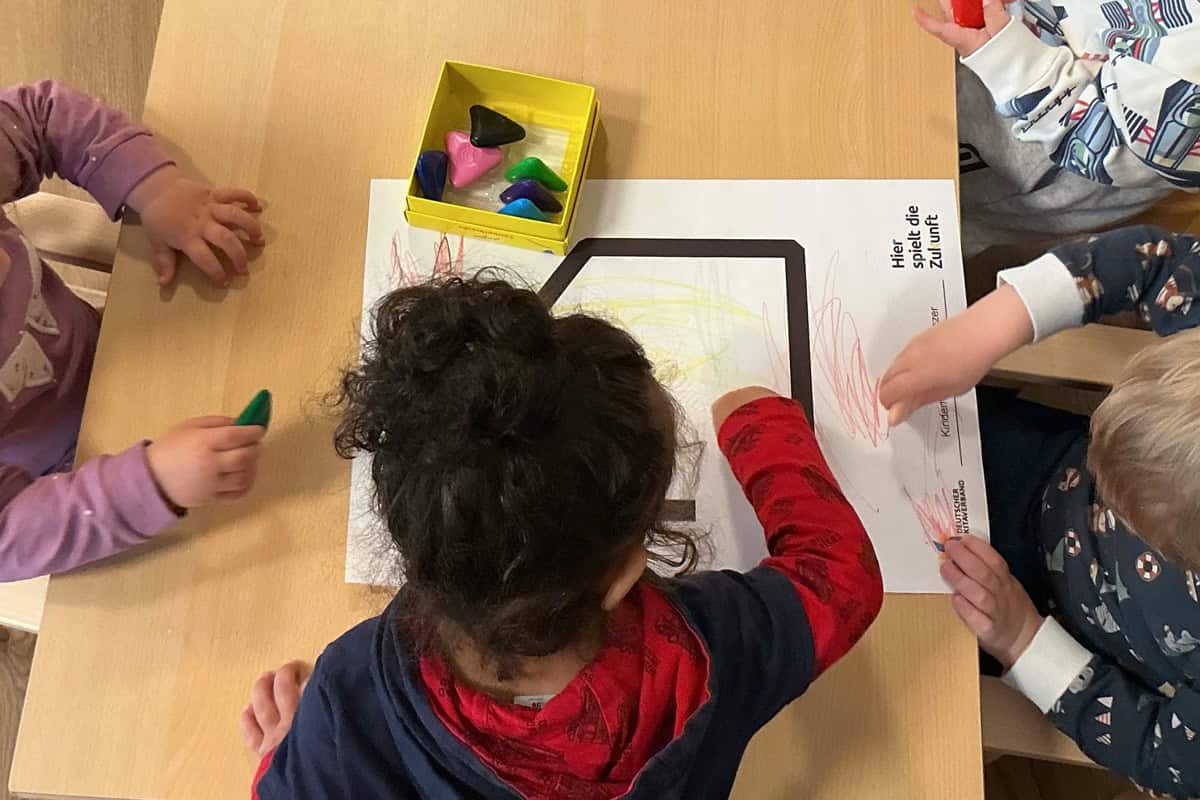 Kinder beim kreativen Malen mit Buntstiften an einem Tisch.
