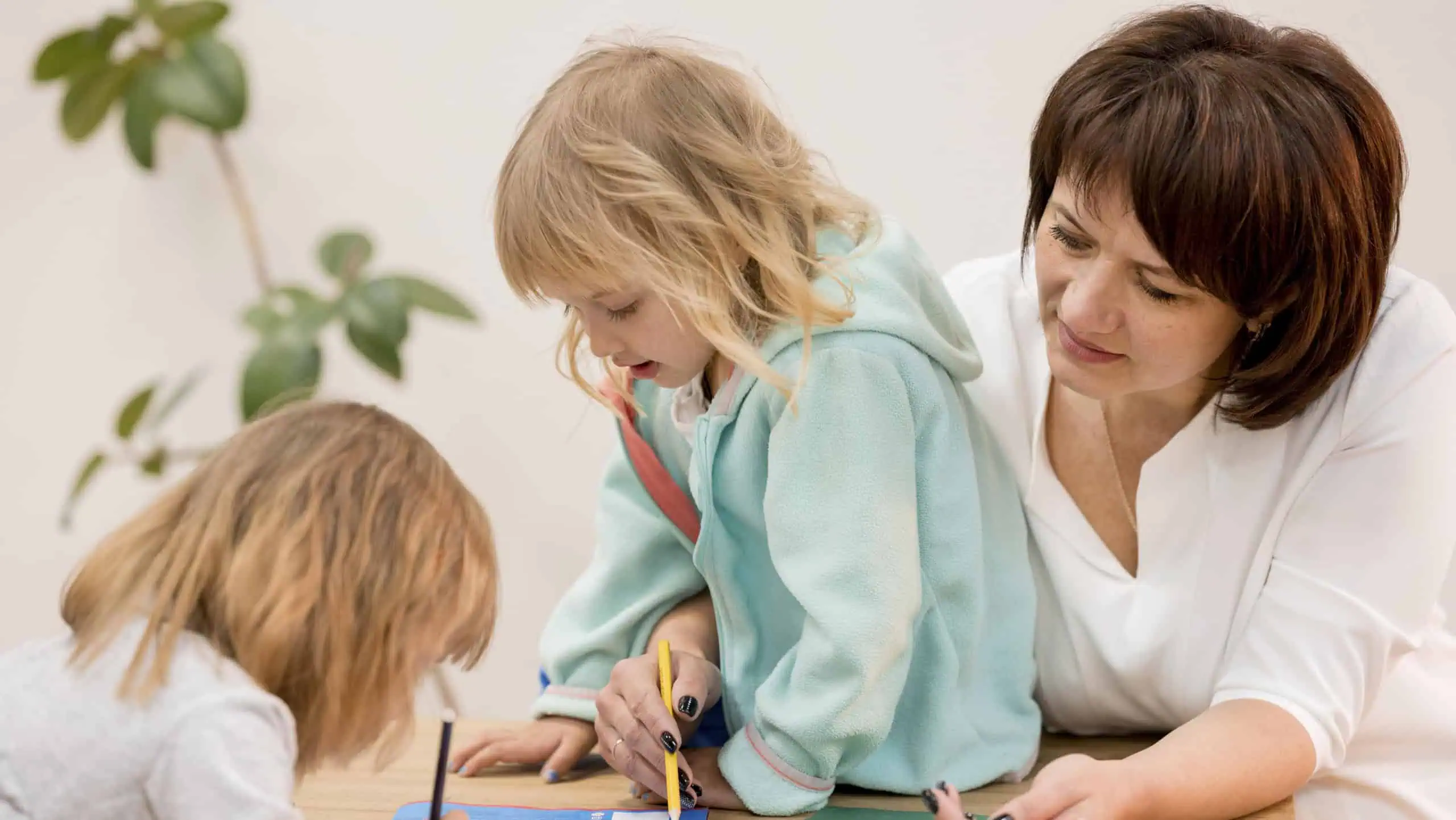 Kinder und Betreuerin beim kreativen Malen im Kindergarten.