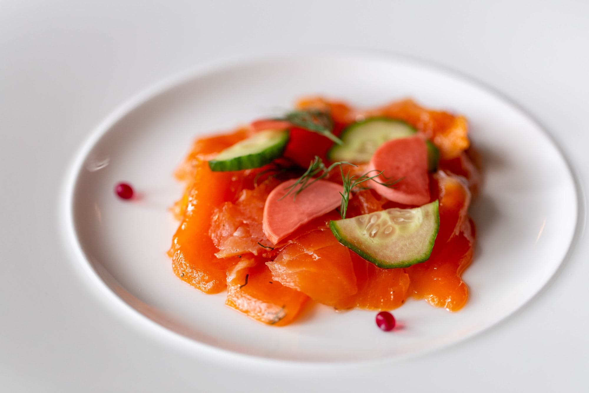 Delicious smoked salmon served with fresh cucumber slices and cherry tomatoes, perfect for a refined.