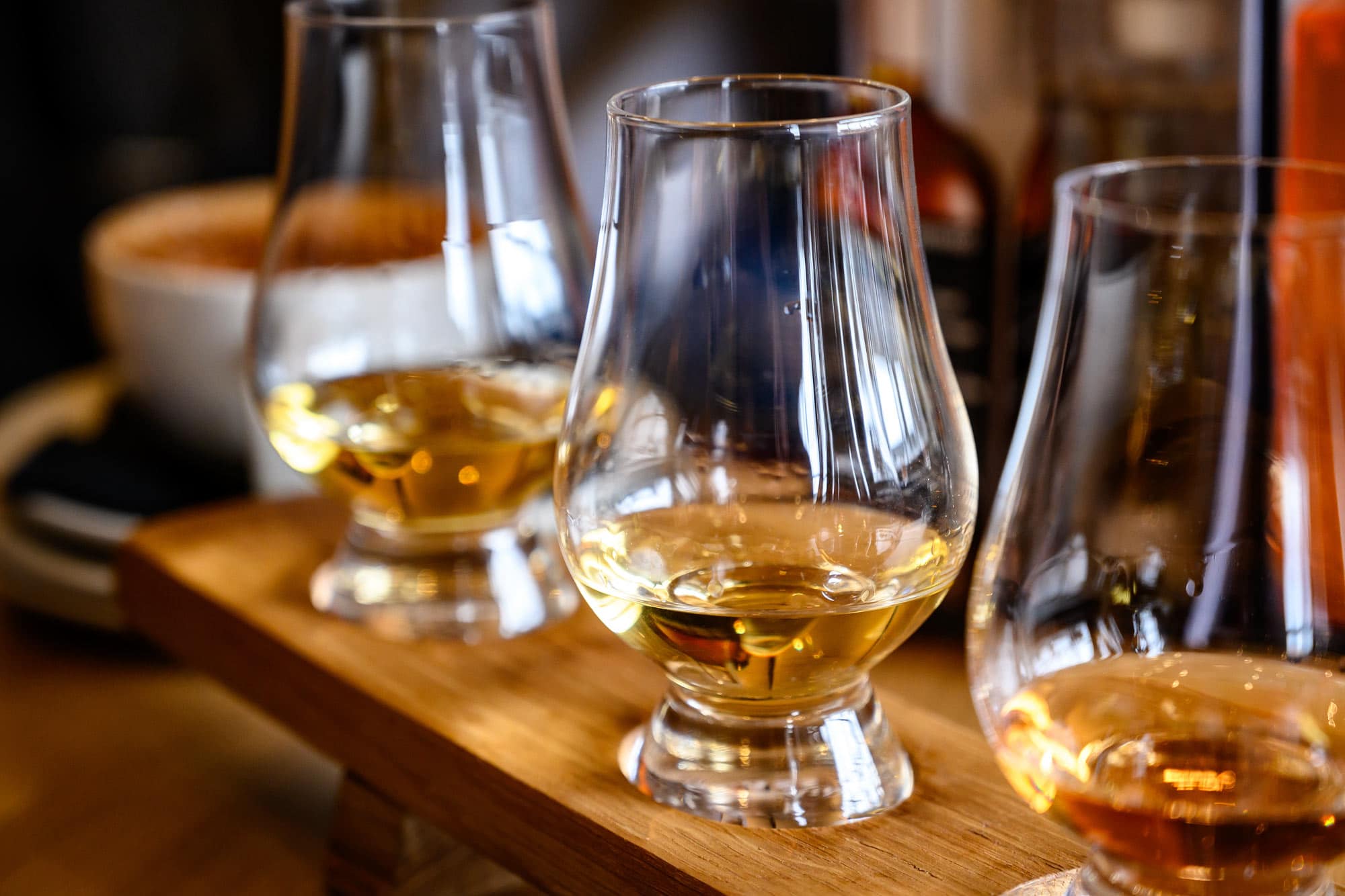 Three whisky glasses on a wooden tasting board at Dowans Hotel Speyside.