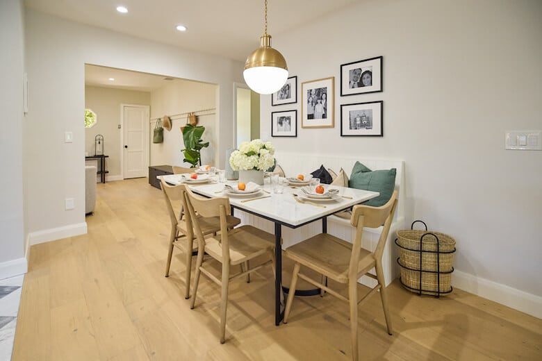 Modern dining nook with a marble table, wooden chairs, and a cozy bench