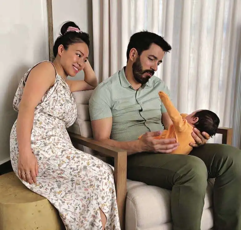 Drew holding baby Parker in orange outfit while Linda in floral dress smiles beside them