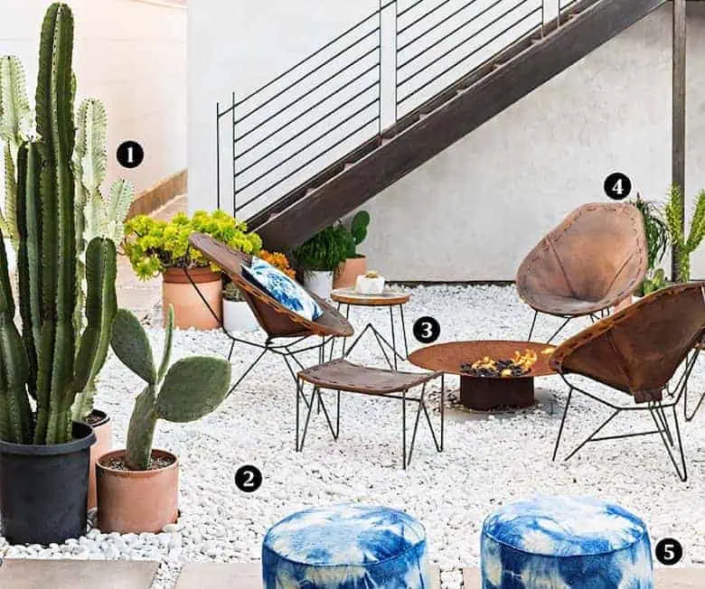 Modern outdoor patio with cacti, leather chairs, a fire pit, and blue tie-dye poufs