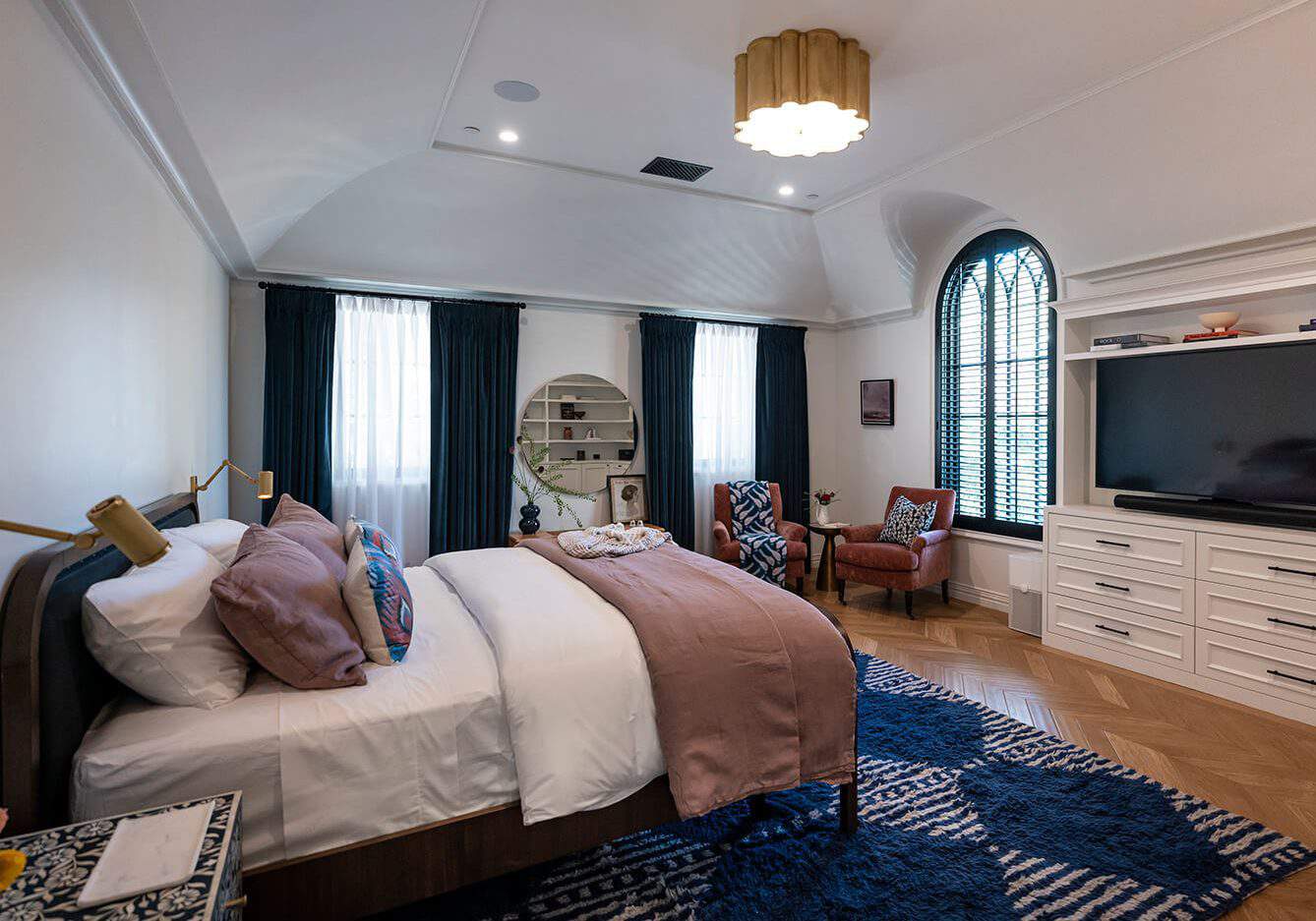 Cozy bedroom with plush bedding, deep blue curtains, and elegant furnishings