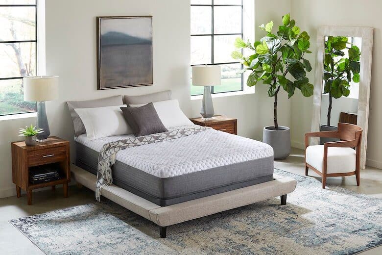 Modern bedroom with a low-profile bed, wooden nightstands, a large mirror, and a potted plant