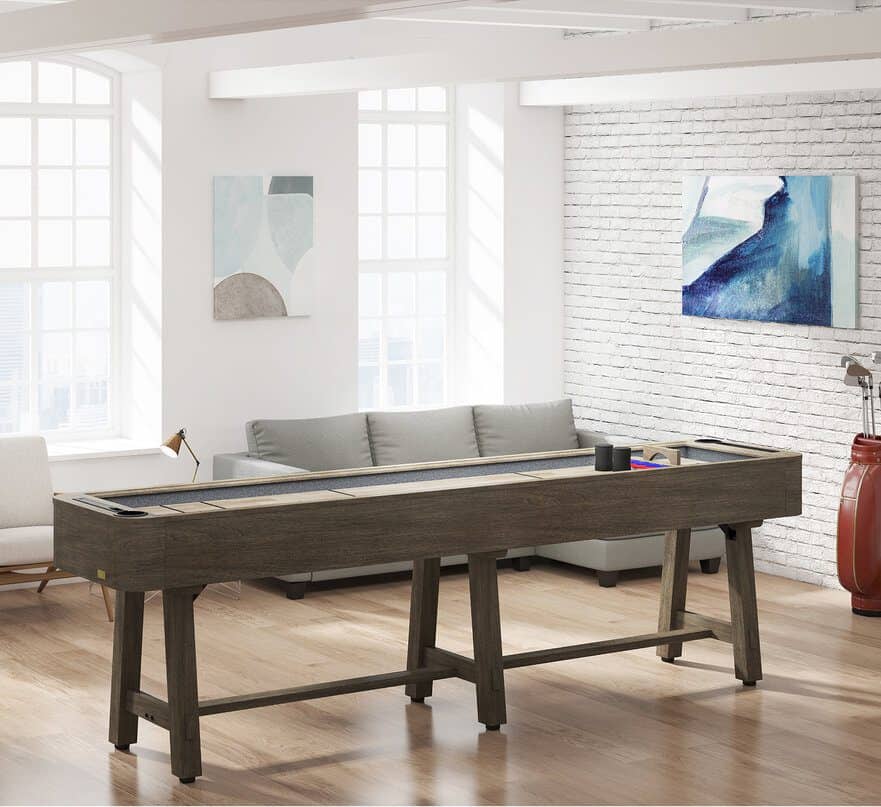 Game room featuring a dark wood shuffleboard table, a gray sectional sofa, large windows, and abstract wall art