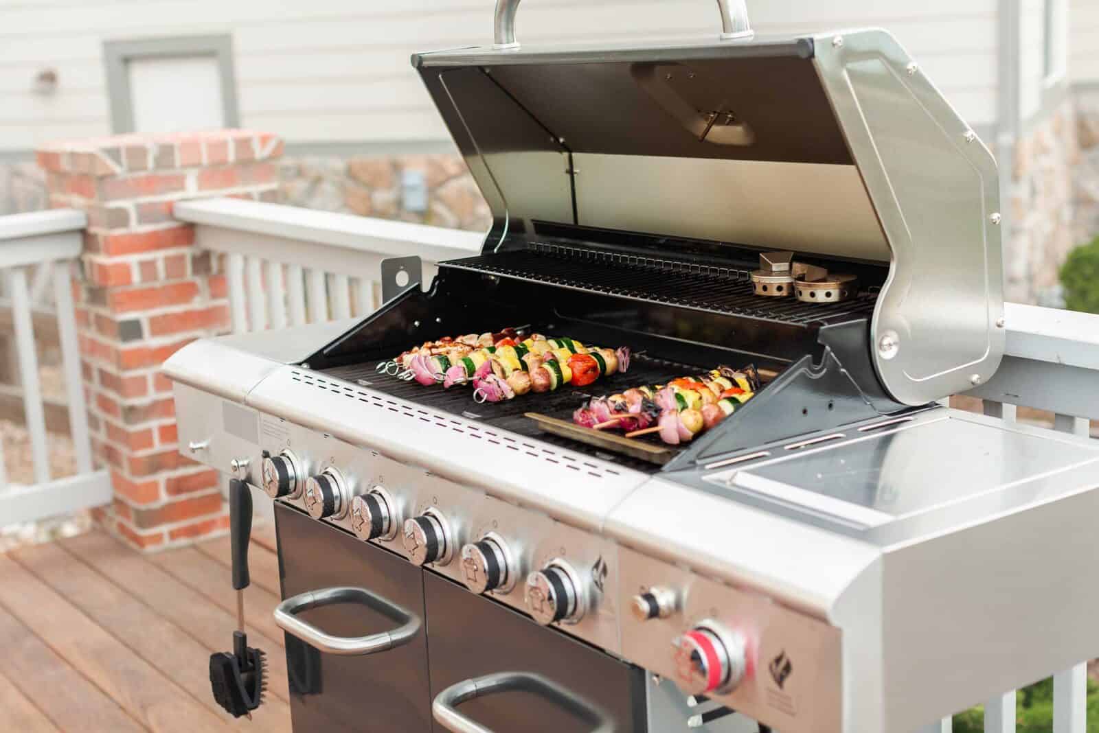 Stainless steel outdoor grill with skewers of grilled vegetables and meats