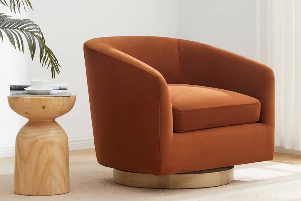 Modern rust-colored swivel chair next to a wooden accent table with a cup and magazine
