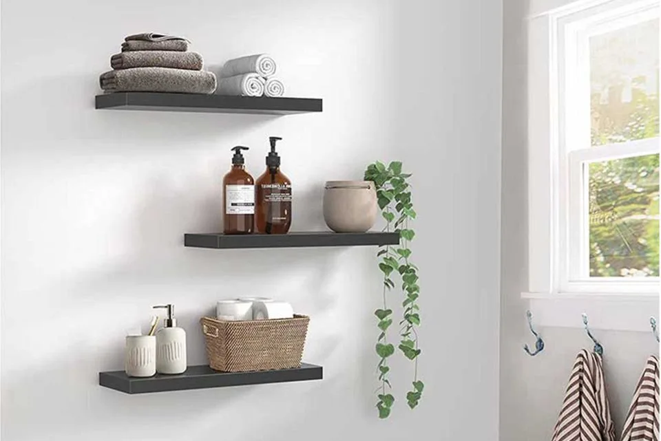 Wall-mounted shelves with towels, toiletries, and a hanging plant in a bright bathroom