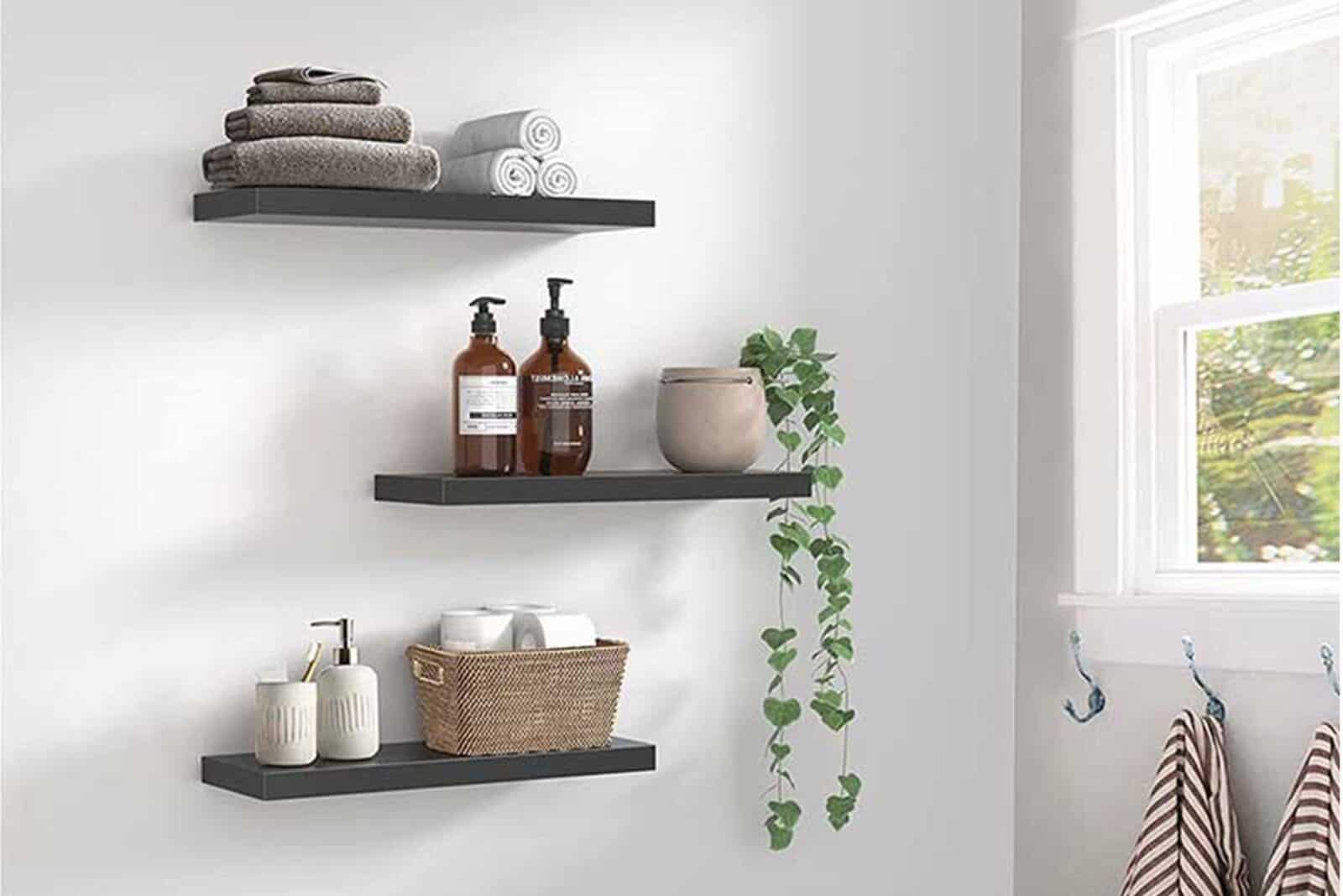 Wall-mounted shelves with towels, toiletries, and a hanging plant in a bright bathroom