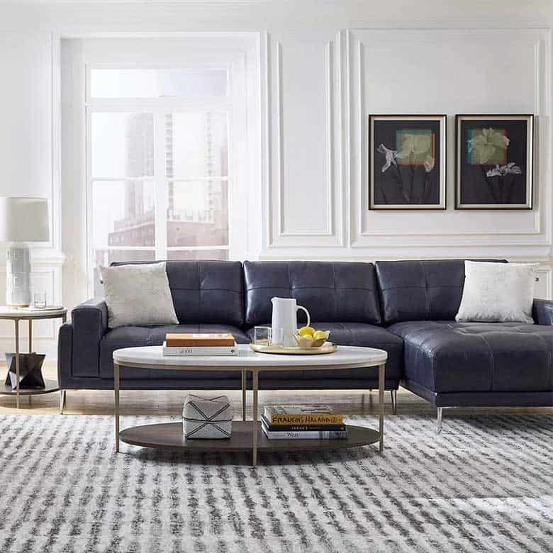 Modern living room with a navy leather sectional, round white coffee table, and minimalist decor