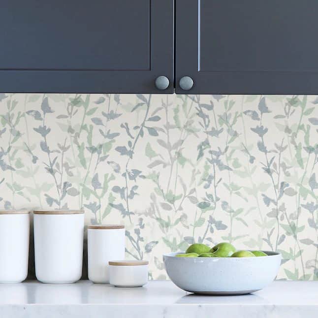 A kitchen with a white counter and a green wallpaper