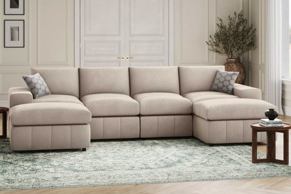Light beige sectional sofa with decorative pillows, coffee table, and a potted plant in a living room