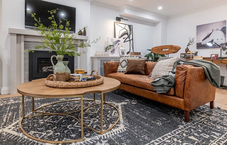 Stylish living room with brown leather sofa, round wooden coffee table, and dark patterned rug