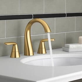 Modern bathroom sink with a brushed gold faucet set and running water