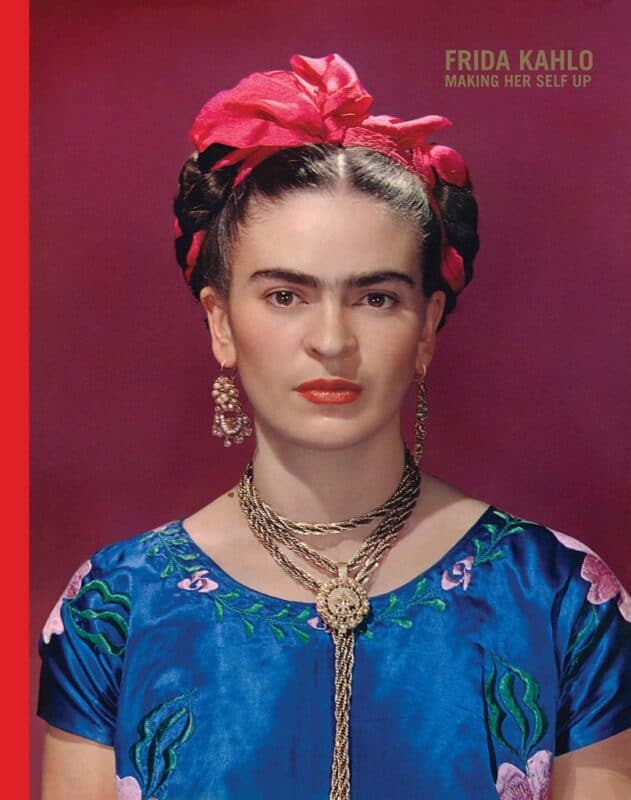 Frida Kahlo in traditional attire with a vibrant pink headpiece and bold jewelry