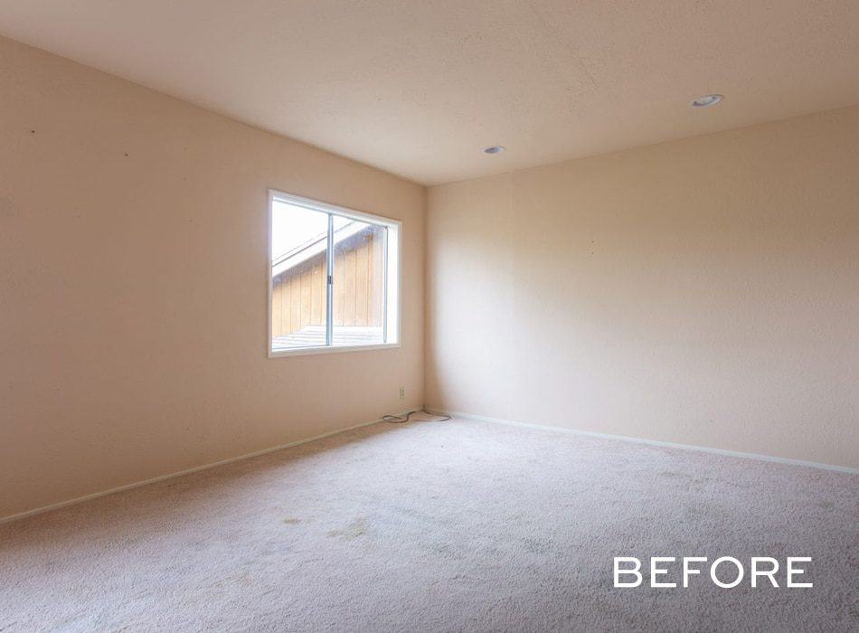 Empty beige room with a window, carpeted floor, and recessed lighting