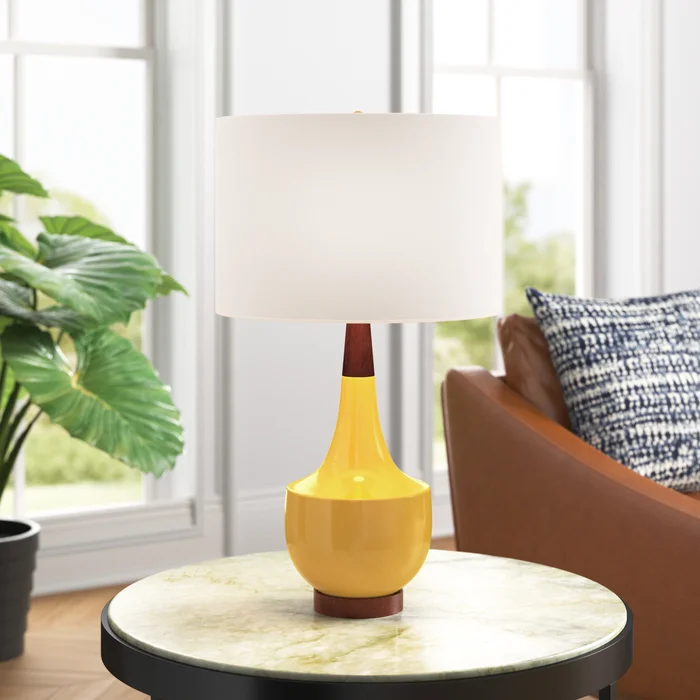 A mid-century modern table lamp with a vibrant yellow base and a classic white shade