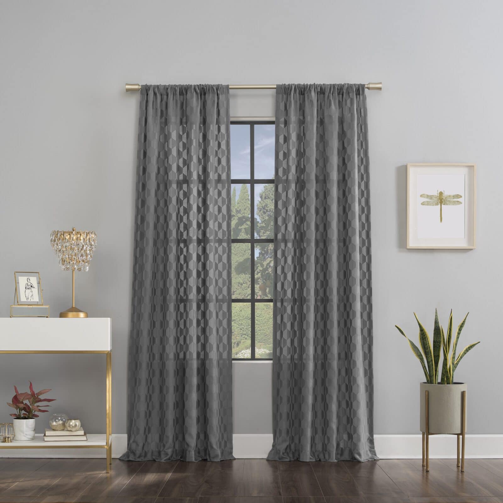 Sheer gray curtains with geometric pattern hanging on a brass rod in a modern living space