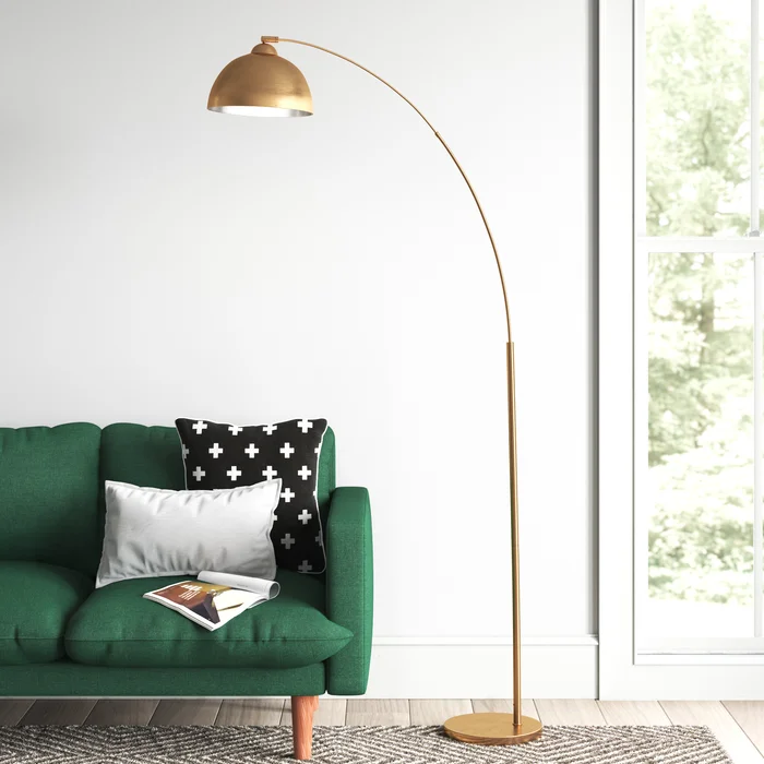 Modern living room with green sofa, gold arc floor lamp, and black and white pillows