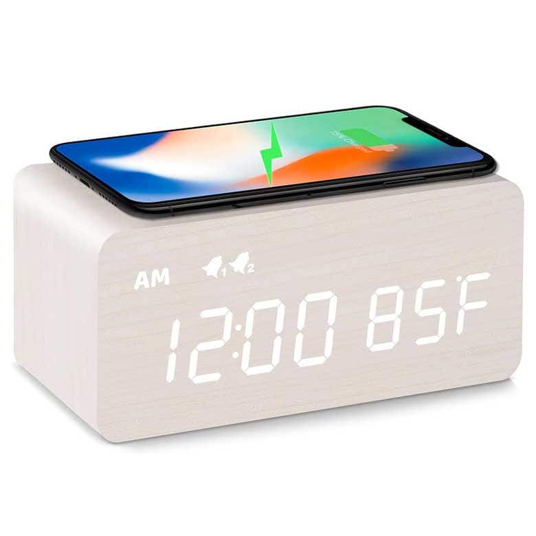 Wooden alarm clock with a digital display and a smartphone charging on top