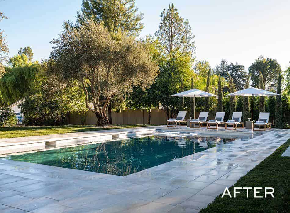 An after image of a luxurious backyard with a rectangular swimming pool surrounded by lounge chairs and umbrellas