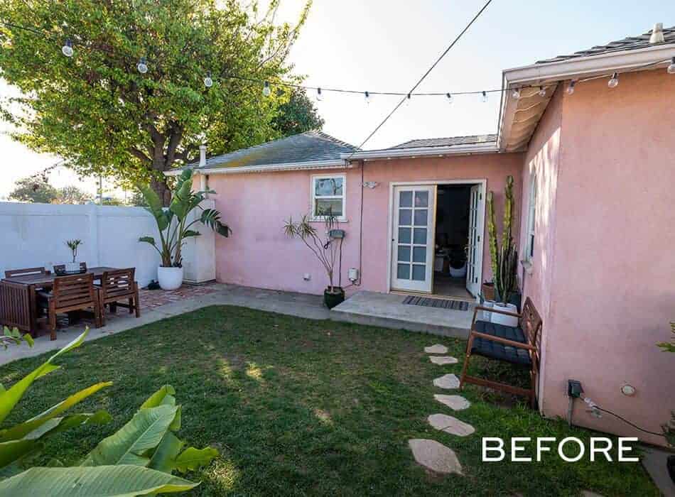Before renovation: A dated backyard with a pink house and a concrete patio
