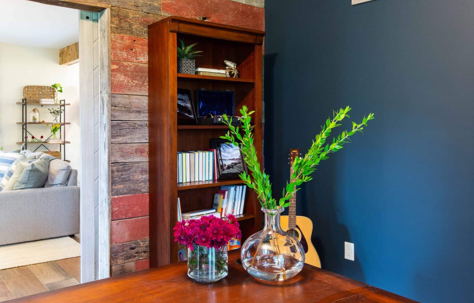 Rustic room with wooden bookshelf, blue accent wall, and floral vase decor