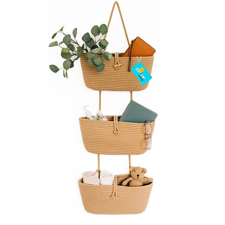 Three hanging woven baskets made of natural jute rope, with gold-toned metal accents, holding various items
