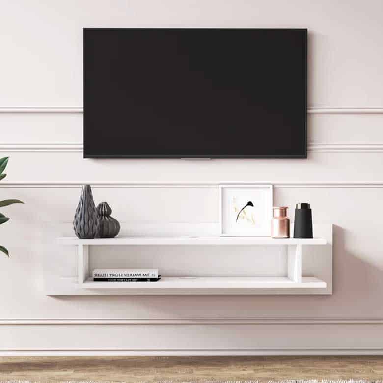 Wall-mounted TV above a sleek white floating shelf with minimal decorative items and a book