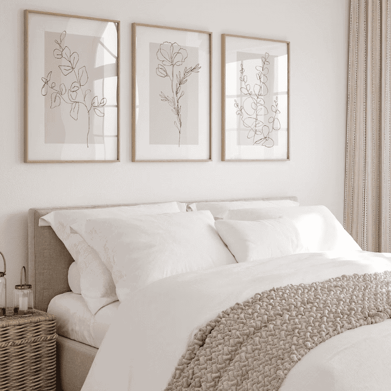 Neutral bedroom with white bedding, line art, and soft natural light