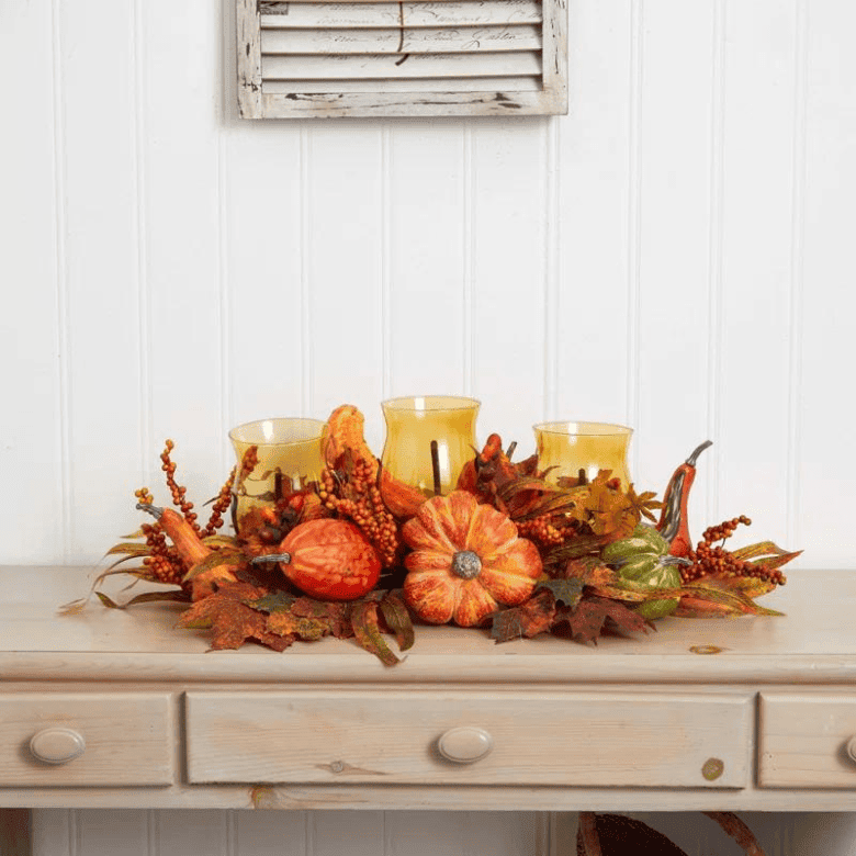 Fall centerpiece with pumpkins candles and autumn leaves on wood console table