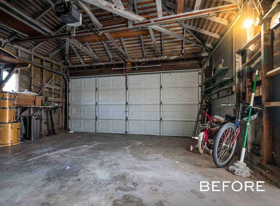 Empty garage with exposed wooden beams and stored items like a bike and drum set