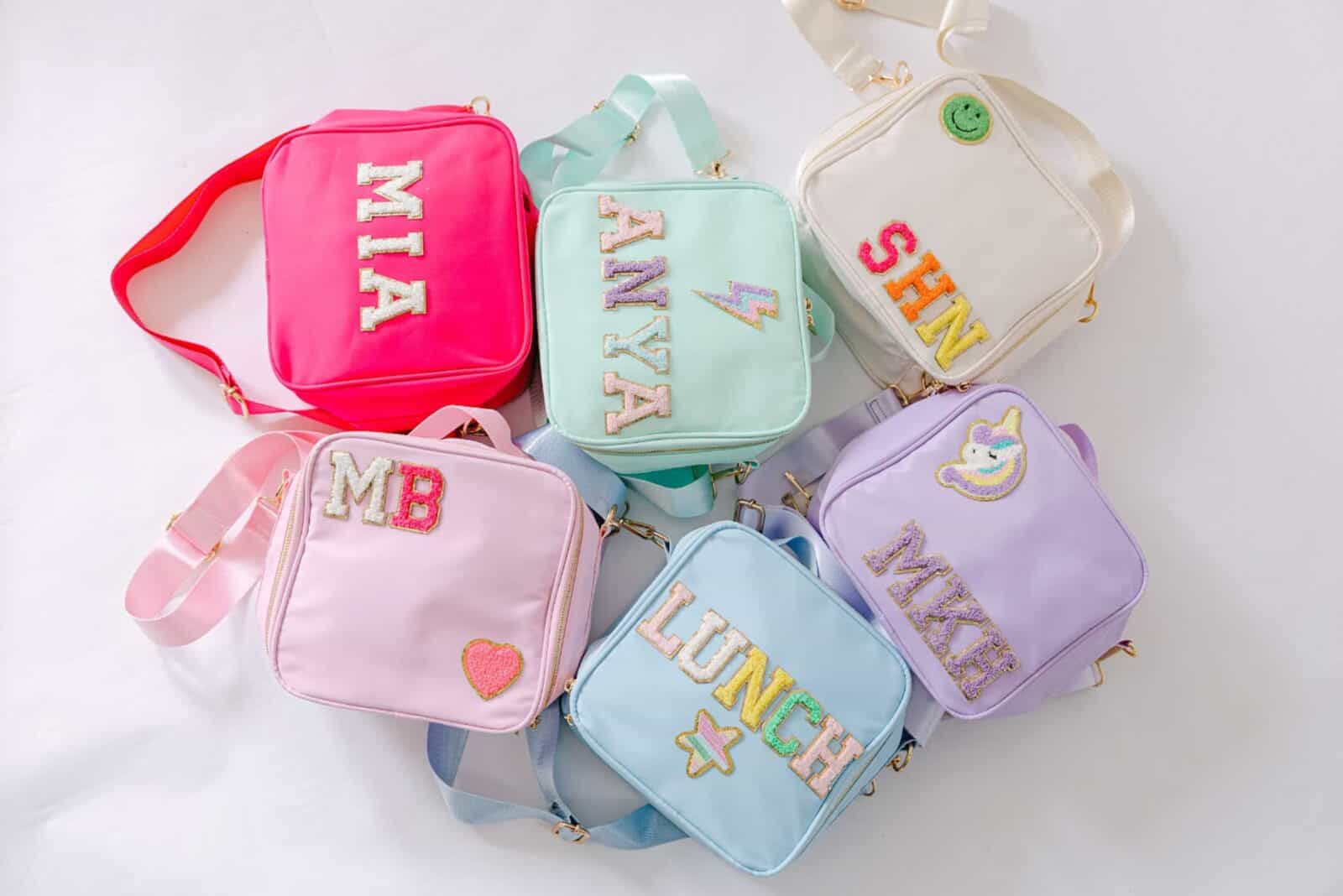 Colorful personalized backpacks with sequined initials and designs, including hearts, unicorns, and stars