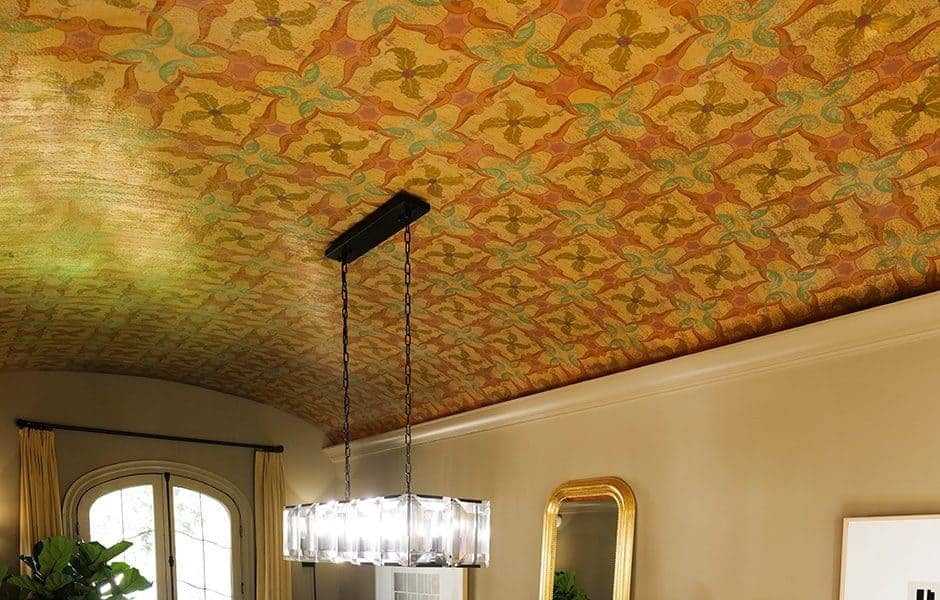 Room with a patterned gold and green ceiling, modern chandelier, and neutral walls