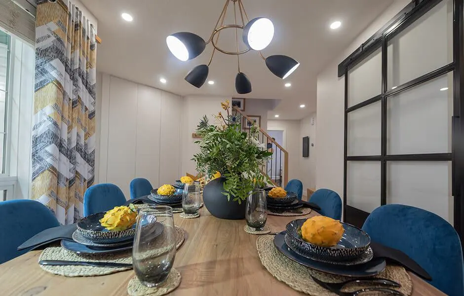 Dining room with wooden table, blue chairs, and contemporary chandelier.