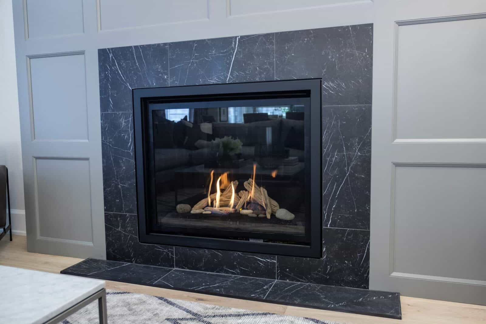 Modern gas fireplace with black marble tile surround and light gray paneled walls