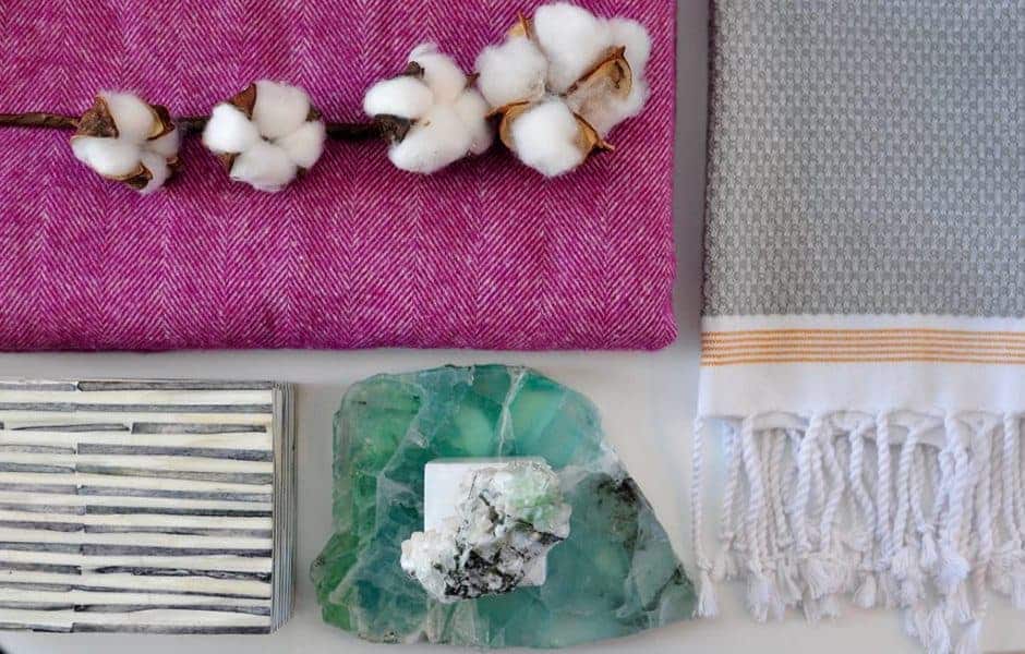Decorative flat lay with cotton branch, magenta and gray textiles, striped tiles, and green mineral stone centerpiece
