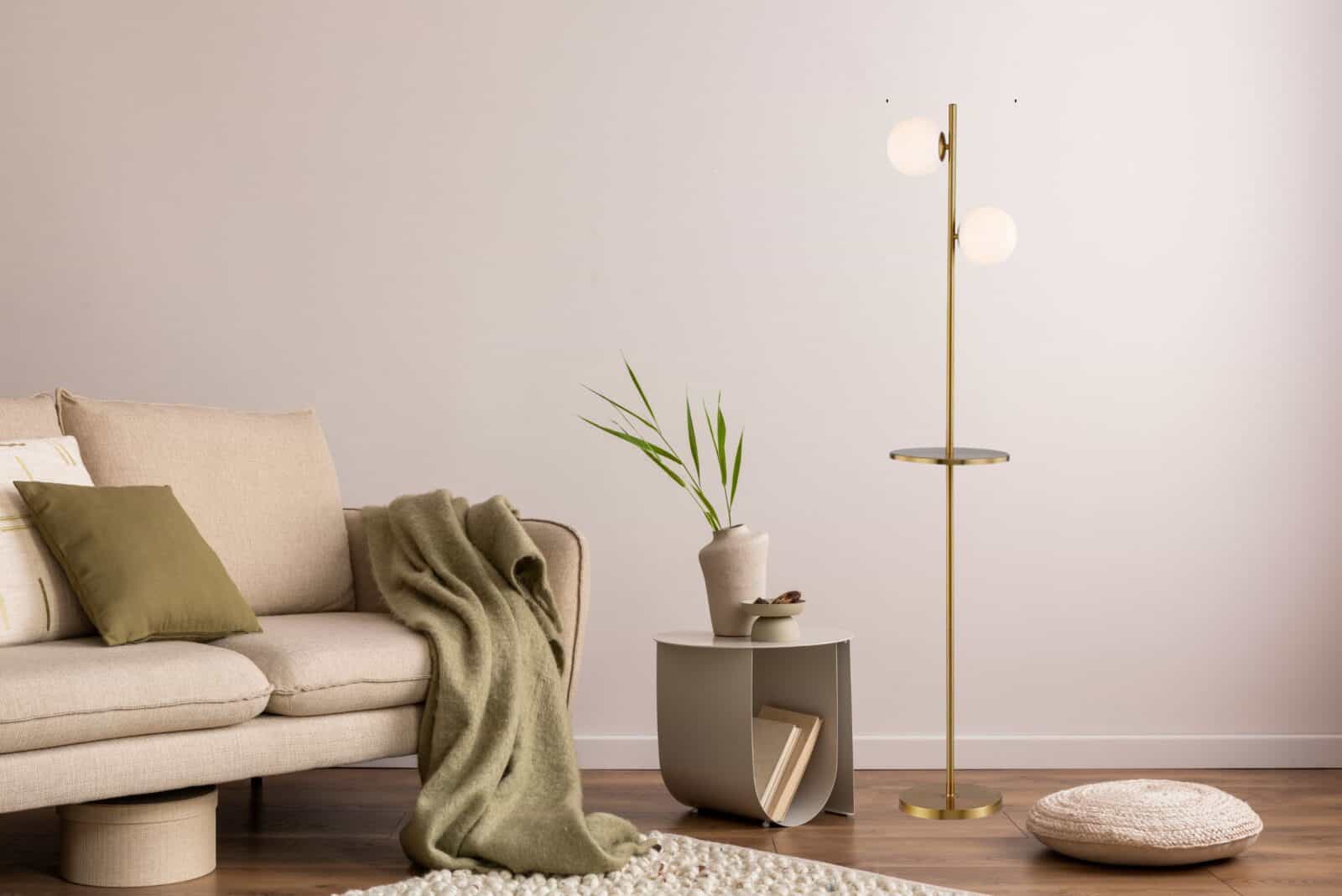 Minimalist living room with a beige sofa, modern floor lamp, and a small side table with a vase and books