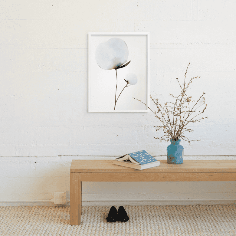 Minimalist entryway with wooden bench, blue vase, and cotton wall art