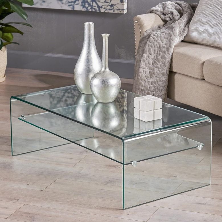 Glass coffee table with silver vases and a white cube sculpture in a modern living room