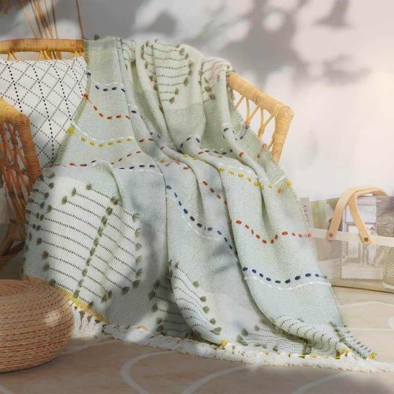 Patterned blanket with colorful dots draped over a rattan chair